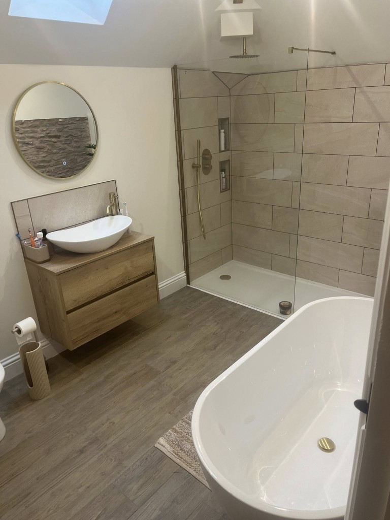 Bathroom with stone-effect shower wall tiles, wood-effect floor and brass fittings