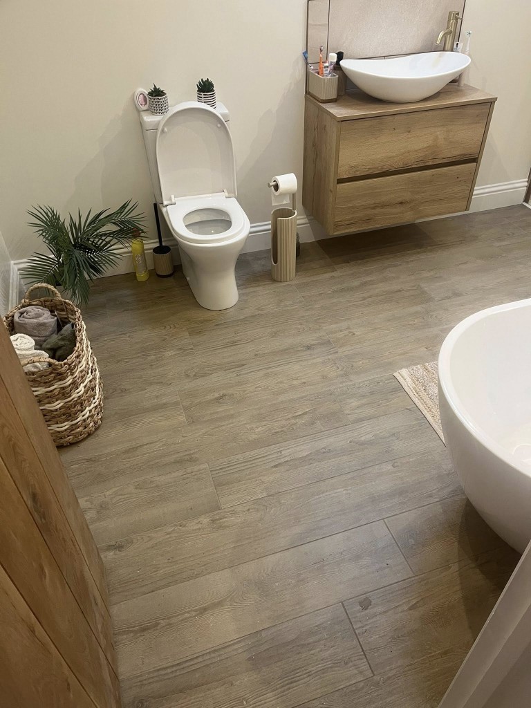 Wood-effect porcelain bathroom floor around a freestanding bath
