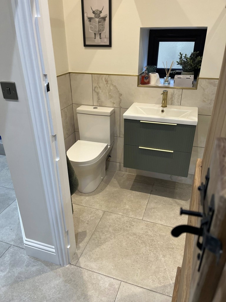 Cloakroom with travertine-effect wall tiles, limestone floor and green vanity