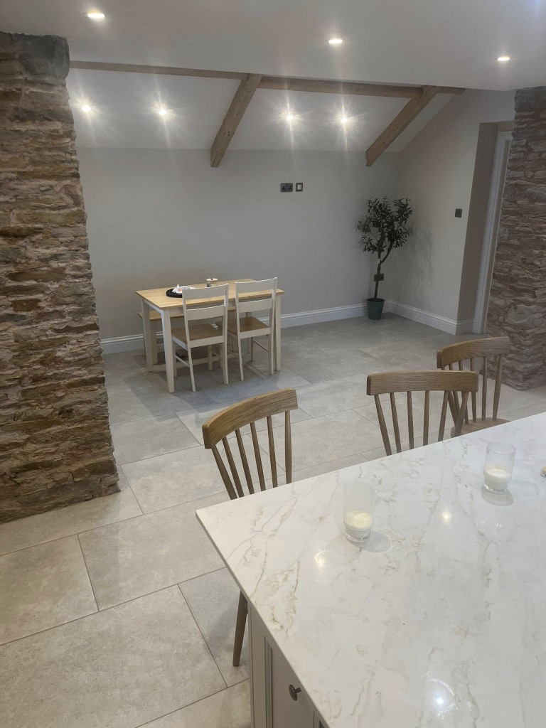 Limestone-effect floor in a beamed dining room with stone pillars