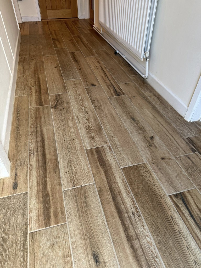 Wood-effect porcelain plank floor through a hallway with tight grout joints
