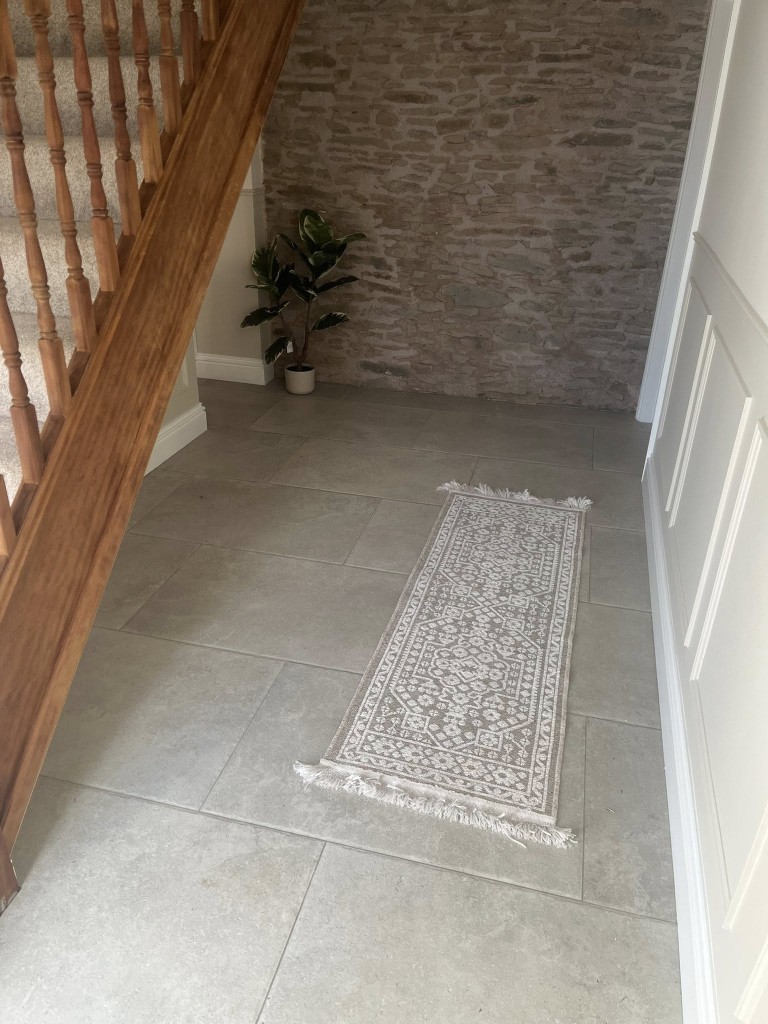Limestone-effect floor tiles in a hallway beside an exposed stone wall