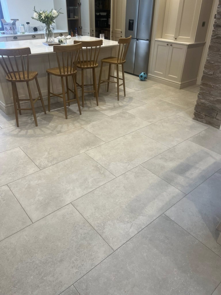 Limestone-effect floor tiles running through an open-plan kitchen