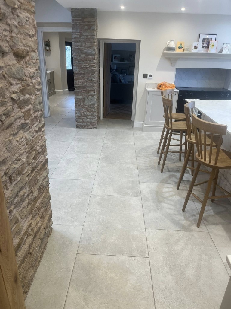Limestone-effect porcelain kitchen floor laid around exposed stone pillars