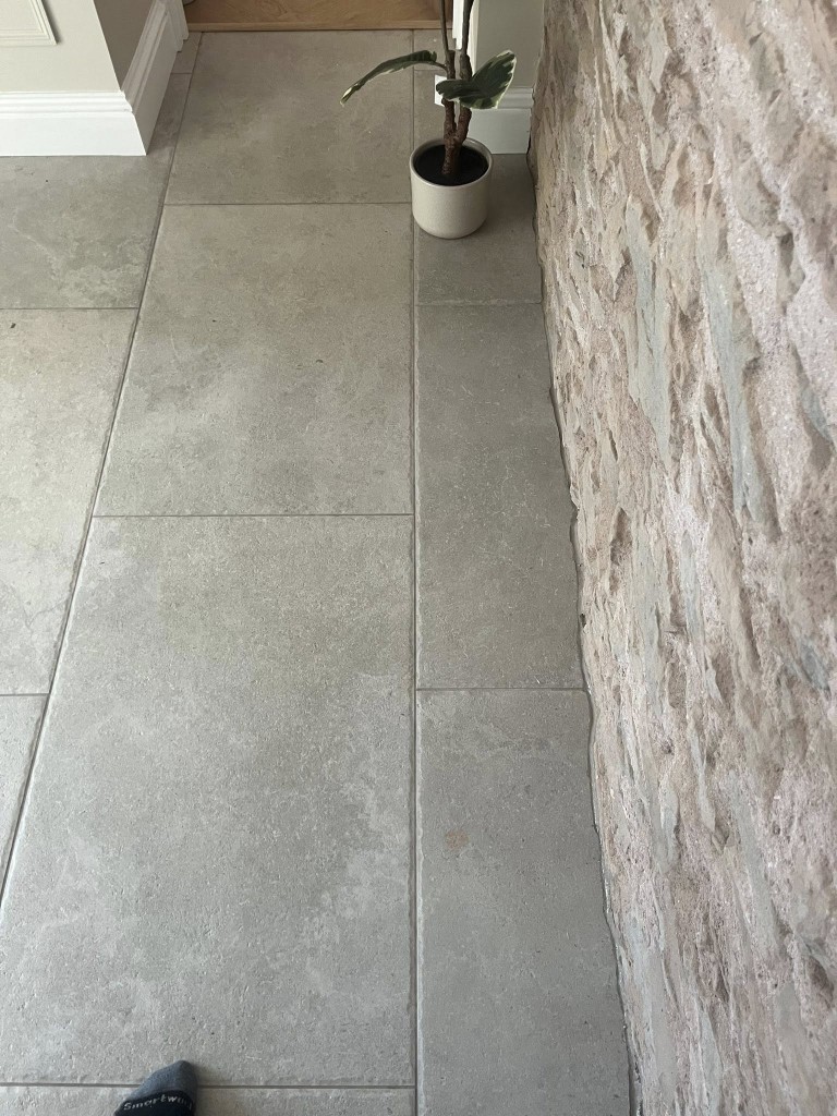 Close detail of limestone-effect tiles scribed against an exposed stone wall
