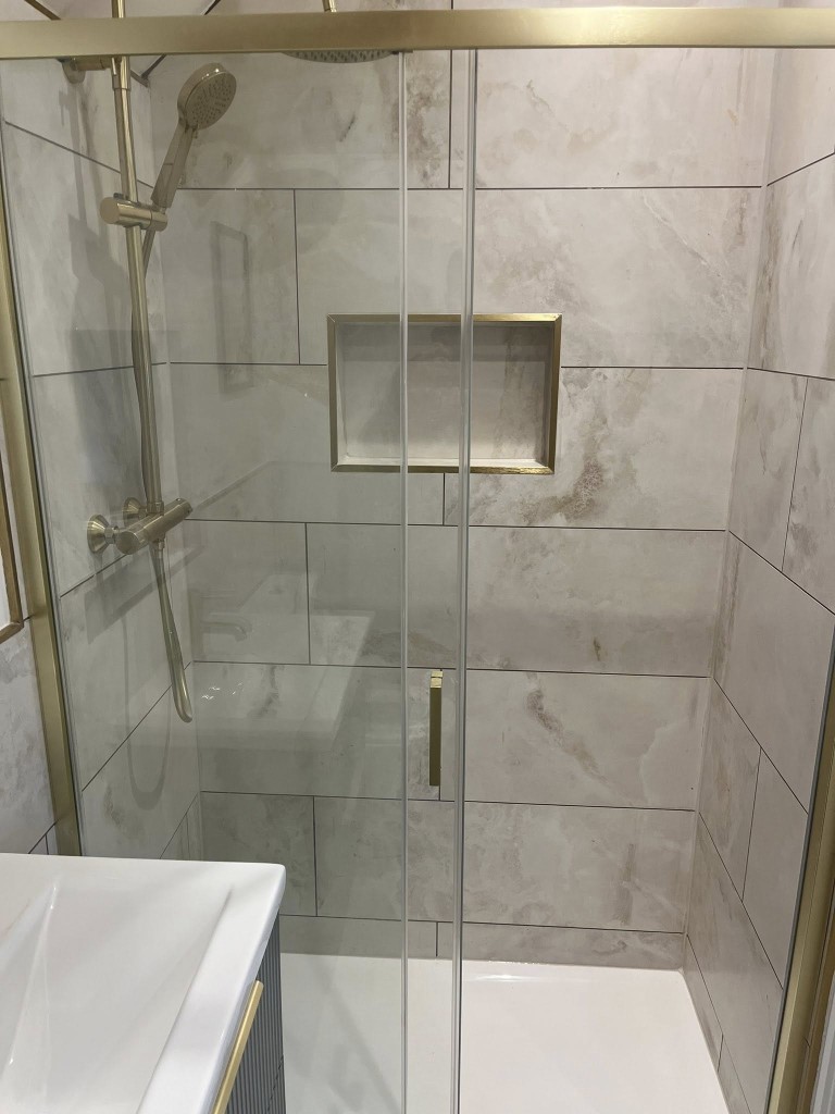 Marble-effect shower enclosure with brass-trimmed recessed niche