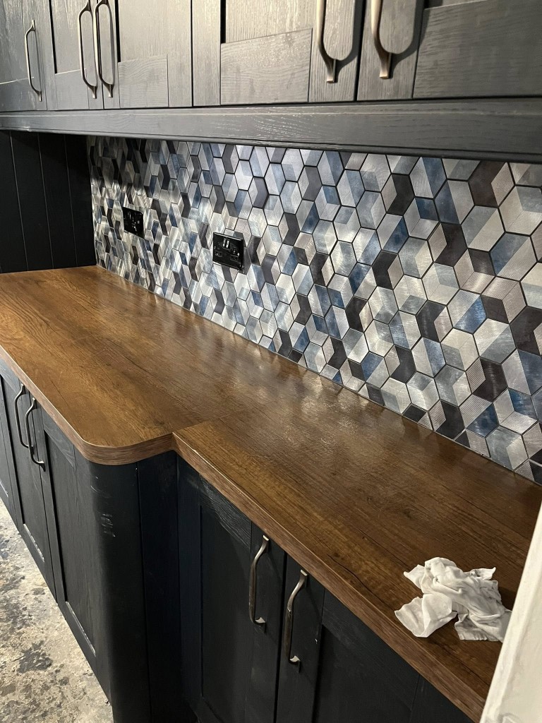 Hexagonal metallic mosaic kitchen splashback against dark cabinetry